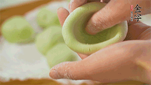 將均分的艾草面團搓成圓，挖一個窩，放入餡心，再搓成圓。