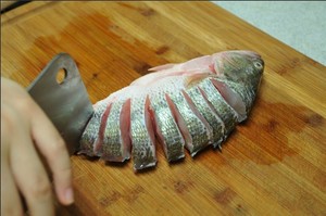 將鱸魚(yú)清洗干凈，從脊椎處切斷至腹部，腹部保留1cm左右不要切斷。