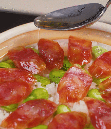 大米出現(xiàn)小孔時(shí)開蓋放香腸，往鍋邊淋入少許油，再燜煮8~10分鐘左右。