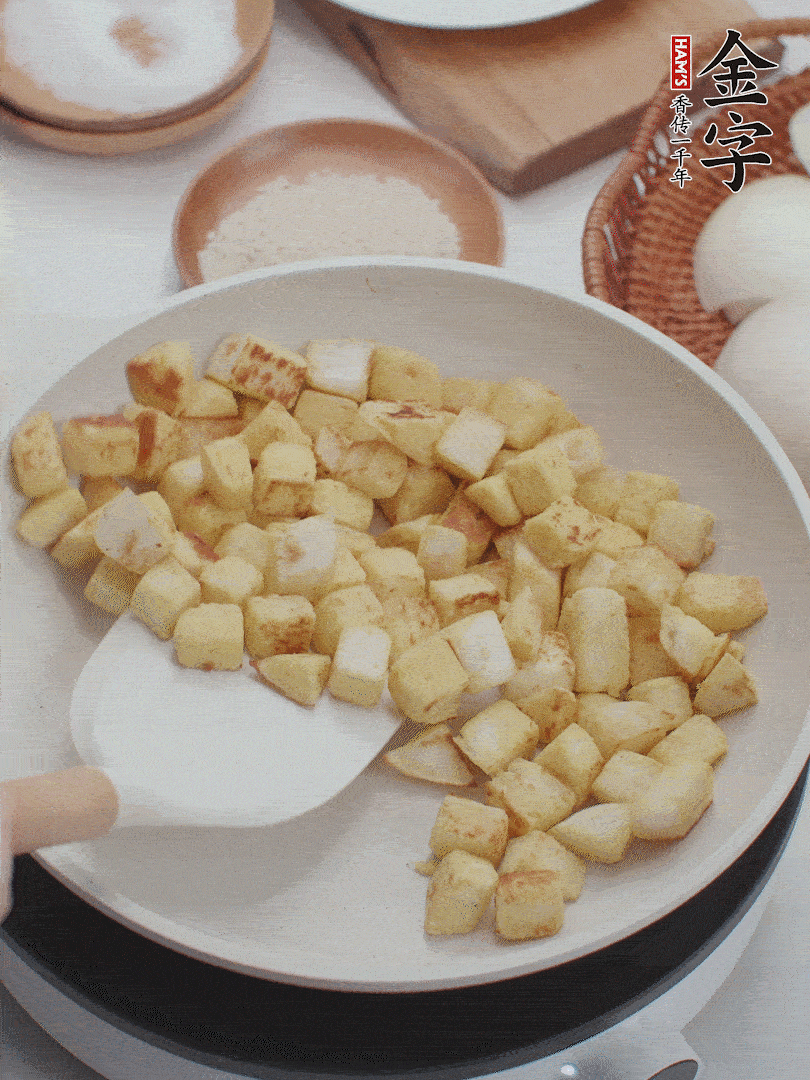 起鍋熱油，倒入饅頭丁，小火煎至蛋液凝固定型再翻面，饅頭丁部煎至金黃時(shí)盛起待用。