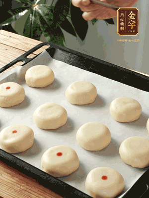 收口向下放在案板上，輕輕將月餅坯按扁，用筷子點(diǎn)紅點(diǎn)做裝飾